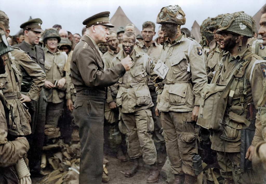 Image shows a colorized photo of General Eisenhower speaking to troops before the invasion of Normandy (D-Day).