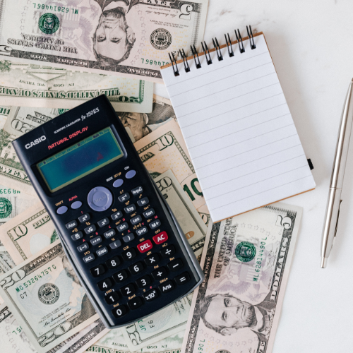 image shows a Casio calculator next to a pen, paper, on top of some American cash.