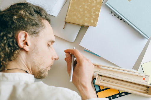 image showing a person lying at their desk, pen in hand but seemingly asleep, showing burnout and overworking