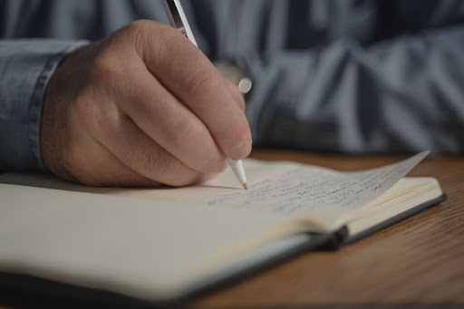 A person writing things down in a notebook to depict crossing out negative skills and “flipping” them
